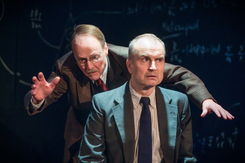 Stephen Riddle as Carl Jung standing behind Jeremy Drakes as Wolfgang Pauli