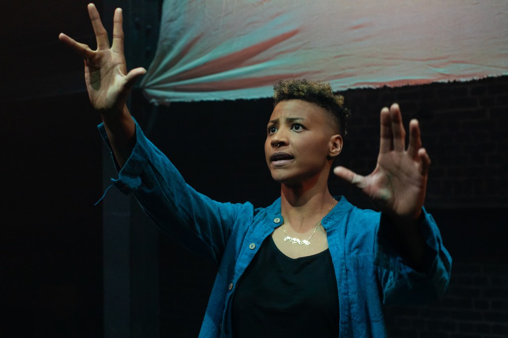 A woman with arms raised addressing the audience