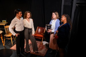 Standing on the right in white shirts and dark trousers Gregory Wilder (played by Thomas Billiouw) and Gloria Wilder (played by Dany Van Brabant) ; standing on the right are Phyllis Amberhide (played by Jess Vince-Moin) and Sherryll-Anne Bowman (played by Kgalalelo Thakadu). Phyllis is holding a collection bucket.